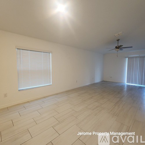 A room with a ceiling fan and wooden flooring.