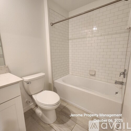 A white toilet and bathtub in a bathroom with white tiles.