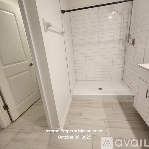 A white tiled bathroom with a walk-in shower and a door.
