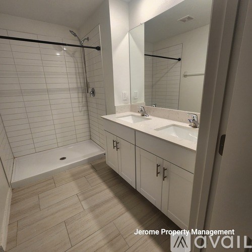 A bathroom with a white tiled shower and a white sink.