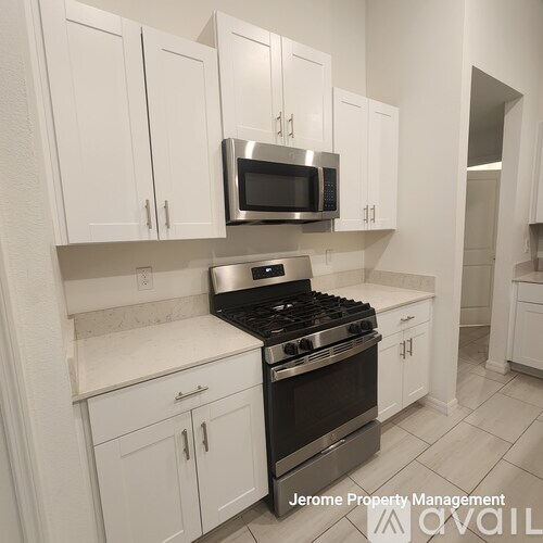 A kitchen with white cabinets and a stainless steel stove and microwave.