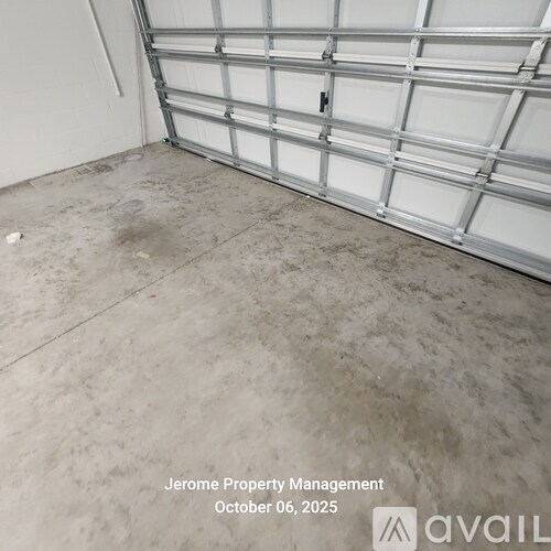 A white garage door is closed and the floor is dirty.