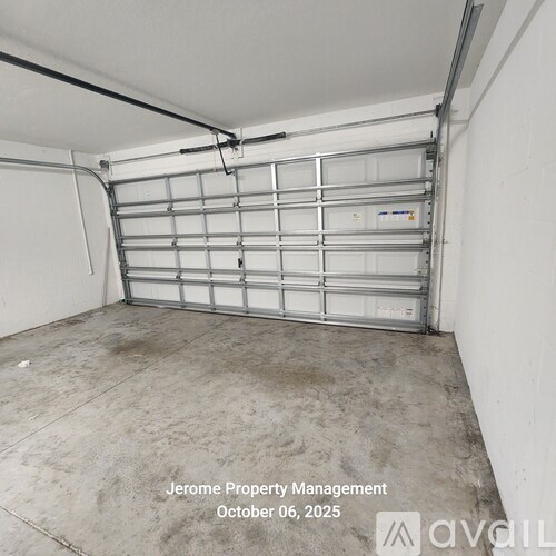 A garage door is closed and the floor is dirty.