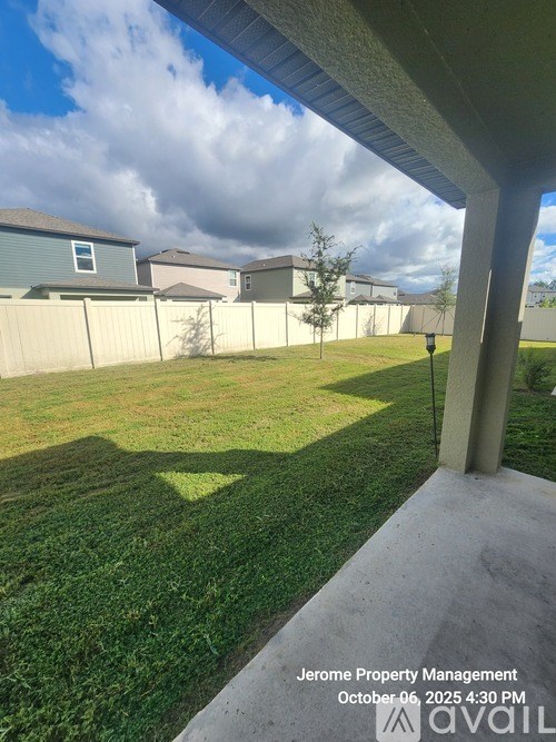 A view from a house looking out to a grassy area with a fence and other houses in the background.