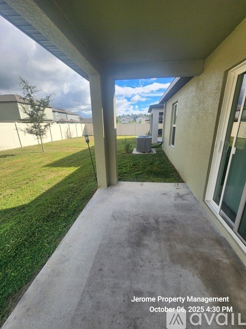 A view of a house's patio with a grassy area and a building in the background.