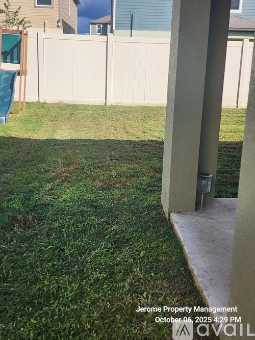 A grassy backyard with a wooden fence and a playground slide.