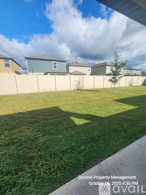 A grassy area with a fence and houses in the background.