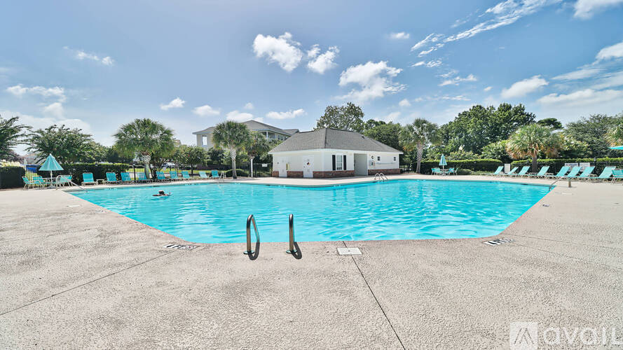 A large swimming pool with a diving board and people swimming.