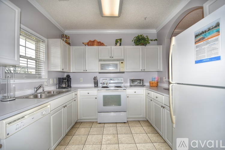 A kitchen with white cabinets and appliances is available for rent.