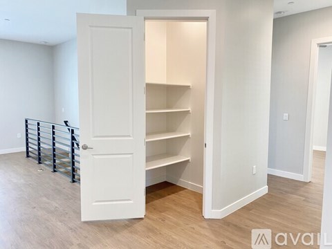 A white door is open to a room with a shelving unit.