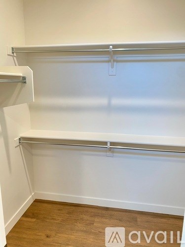 A white wall with a shelf and a wooden floor.