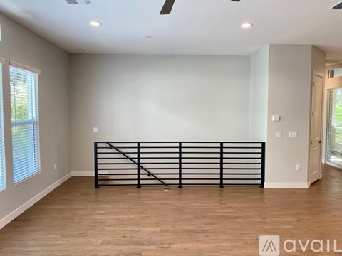 A spacious room with wooden flooring and a black railing.
