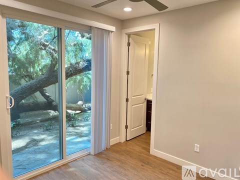 A room with a sliding glass door leading to a forest.