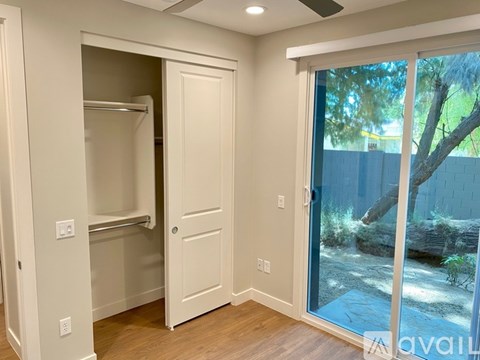 A white closet with a sliding glass door leading to a backyard.