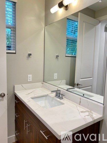 A bathroom with a white counter top and a large mirror.