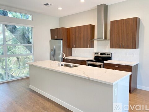 A kitchen with a white countertop and wooden cabinets.