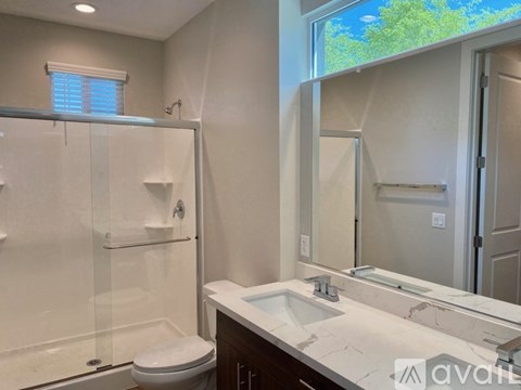 A bathroom with a toilet, sink, and mirror.
