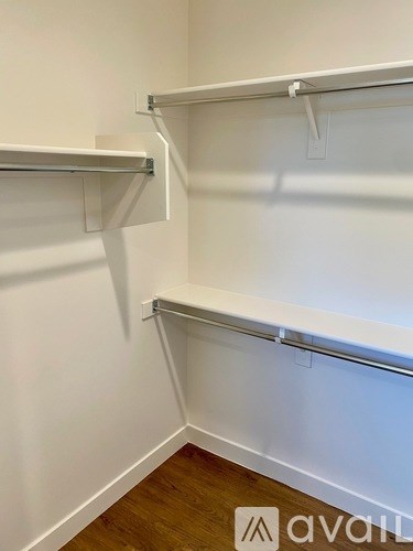 A white wall with two shelves and a wooden floor.