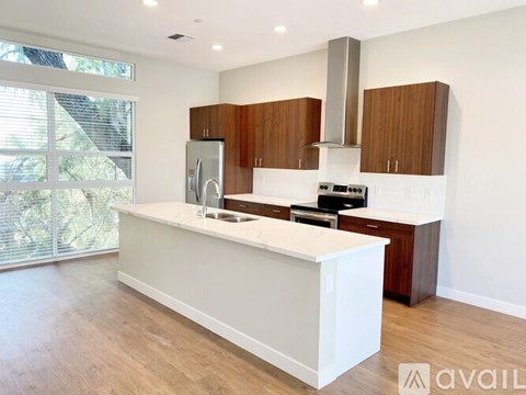 A modern kitchen with a white island and wooden cabinets.