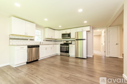 A kitchen with white cabinets and a wooden floor.