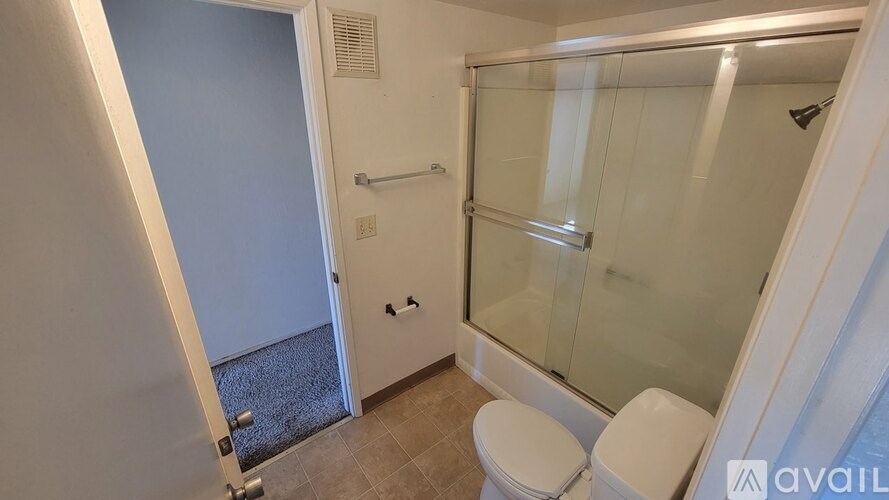 A bathroom with a toilet, a glass shower door, and a glass door leading to a balcony.
