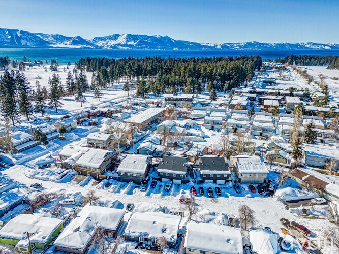 A small town covered in snow with a mountain range in the background.