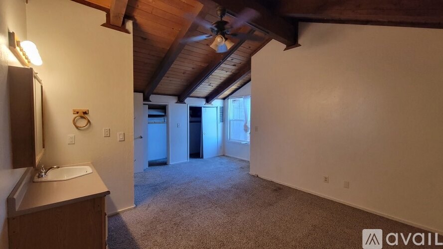 A bathroom with a sink and mirror on the left and a door on the right.