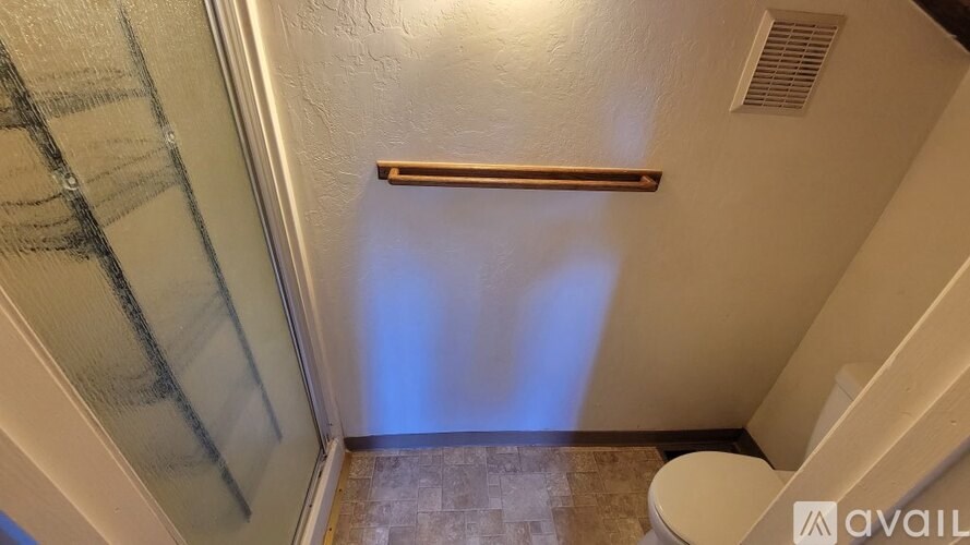 A bathroom with a toilet, a shower with a glass door, and a towel rack.