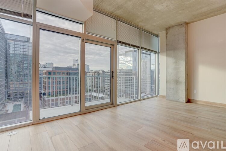 A room with wooden flooring and large windows overlooking a cityscape.