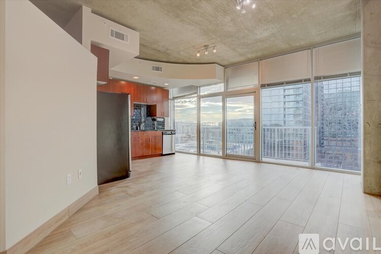 A spacious living room with a kitchen area and a view of the city.
