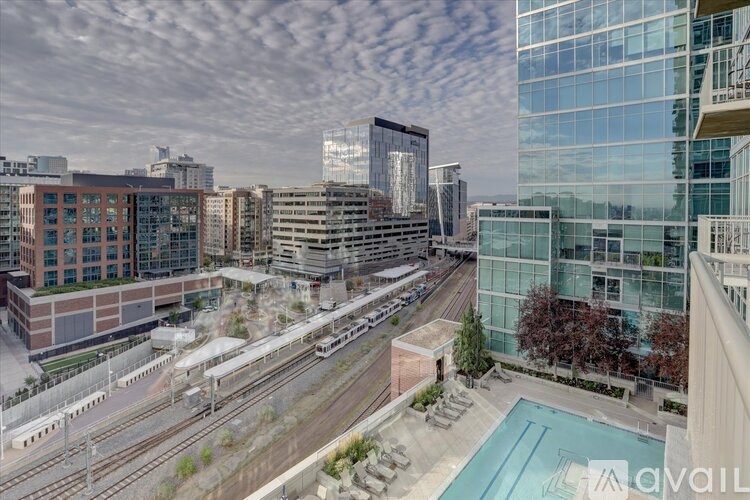 A view of a cityscape with a pool and a train track.