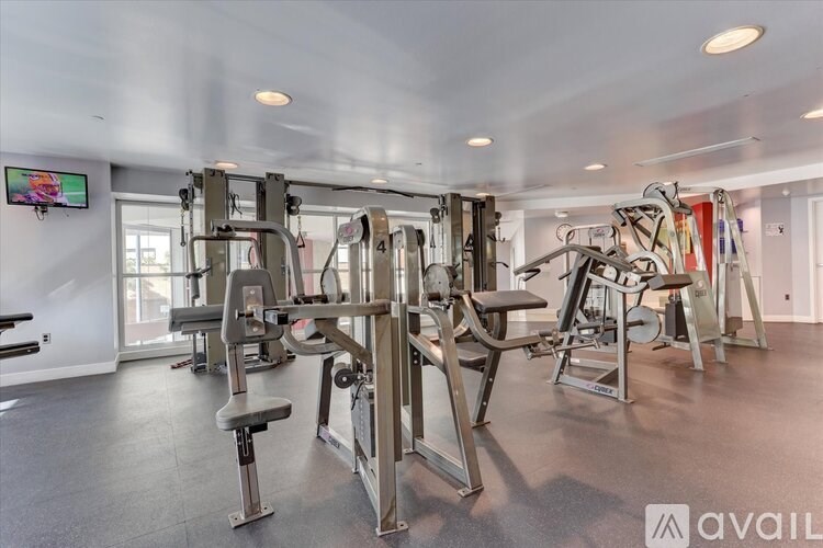 A gym with a variety of equipment including a weight bench, a leg press machine, and a cable machine.