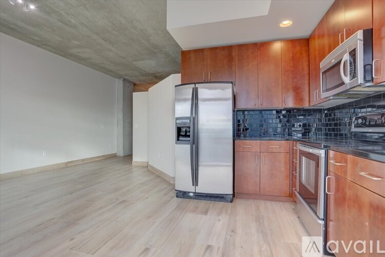 A kitchen with wooden cabinets and a stainless steel refrigerator.