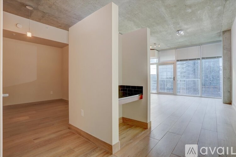A room with a wooden floor and a large window with a view of a city.