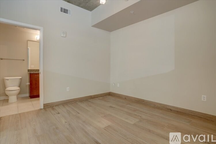 A room with a toilet and wooden flooring.