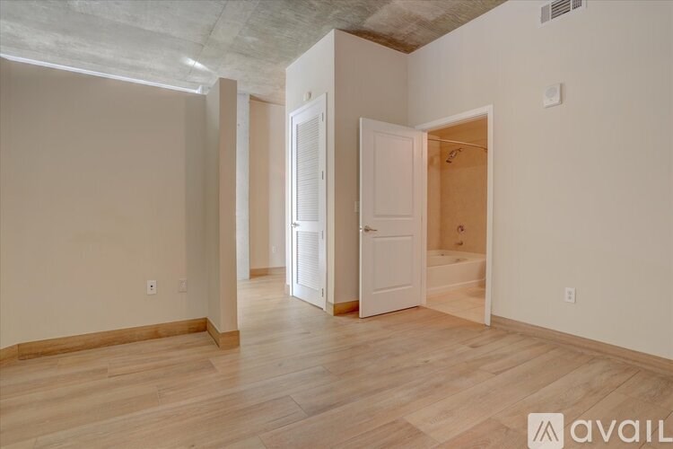 A room with wooden floors and white walls, with a door open to another room.