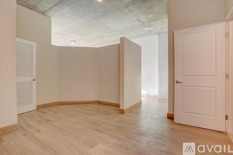 A room with wooden flooring and white walls, with a door on the right side.