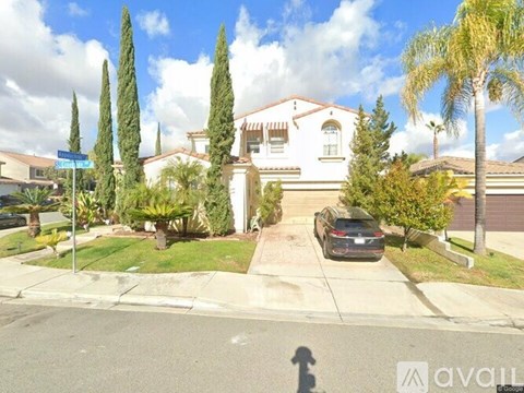 A house with a car parked in front and trees around it.