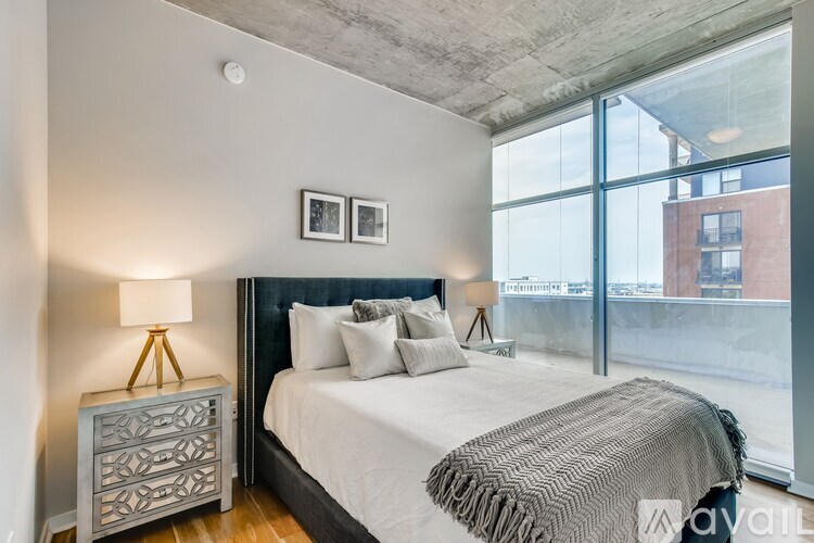 A bedroom with a large bed and a window overlooking a city.