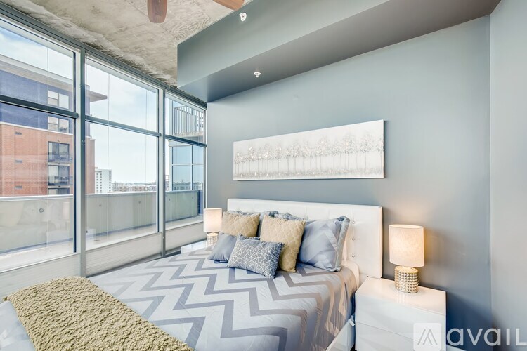 A bedroom with a large bed and a large window overlooking a cityscape.