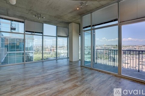 A spacious room with wooden floors and large windows overlooking a cityscape.