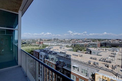 A view from a balcony overlooking a cityscape with buildings and cars.