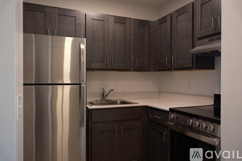 A kitchen with a stainless steel refrigerator and dark brown cabinets.