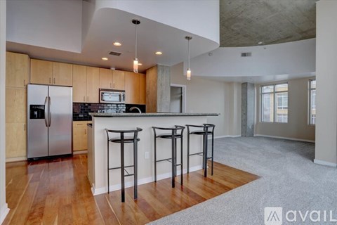 A kitchen with a refrigerator, stove, and bar stools.