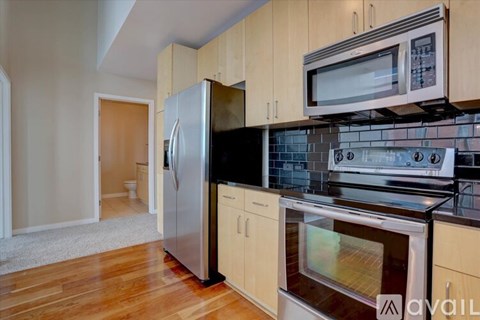 A kitchen with wooden cabinets and a stainless steel refrigerator.