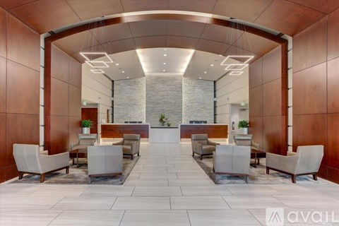 A spacious waiting area with white chairs and a stone wall in the background.