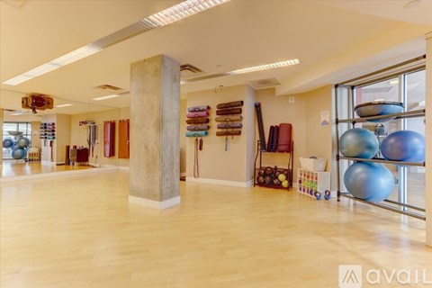 A gym with exercise equipment and a wooden floor.