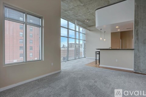 A spacious room with a carpeted floor, large windows, and a bar area.