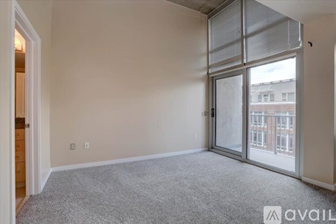 A room with a carpeted floor and a sliding glass door leading to a balcony.