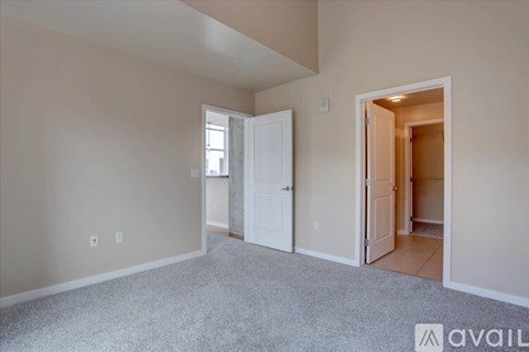 A room with a carpeted floor and two doors, one of which is open.